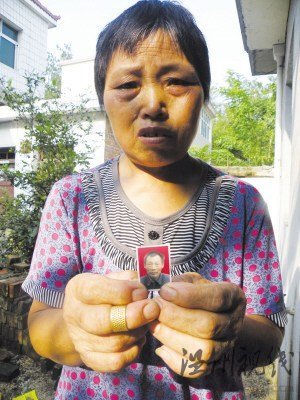 鲍祥义的妻子展示丈夫遗照。