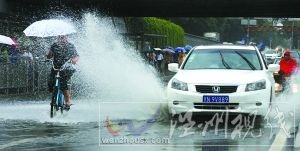 闪 潘家园桥下，汽车掀起的积水飞溅到骑自行车人的身上。本报记者 尹亚飞 摄