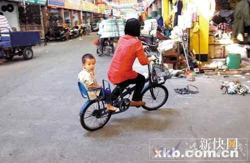 佛山五金市场，一位母亲带着孩子骑车路过事发地点。