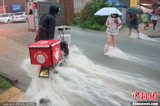 2012年7月21日，北京普降暴雨，朝阳区北部立水桥南地区积水严重。一小区门口，积水沿斜坡形成巨大水流，阻碍人们通行。图片来源：CFP视觉中国